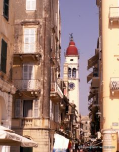 The bell tower of the Saint Spyridon Church can be seen in the background among the busy kantounia of the city center in Corfu, Greece